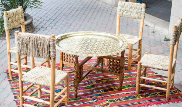 Table basse marocaine en laiton avec socle en bois pliant sur tapis coloré