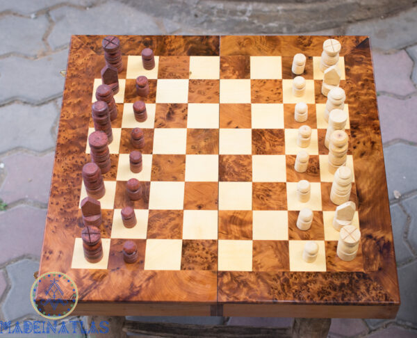 Échiquier en bois de Thuya avec toutes les pièces posées sur une table