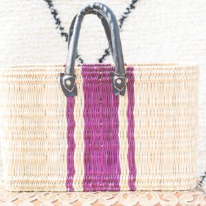 Moroccan market basket in beige color with purple vertical strip and leather straps stand on the table