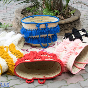Straw beach bag with colored tassels set on the floor in a circle
