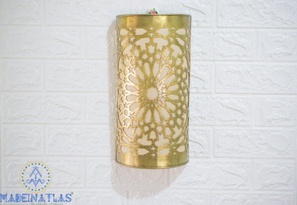 brass wall sconce with geometric design hanging on a white wall background