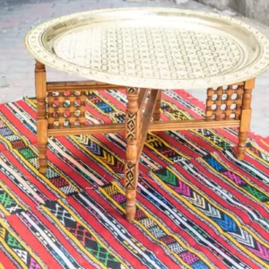Table a the orientale avec plateau en laiton gravé et base pliante élégante en tapis berbère bohème coloré.